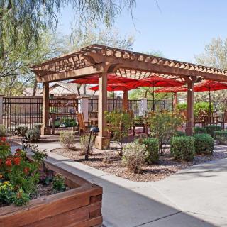 A beautifully landscaped garden with a wooden pergola providing shade to the outdoor seating area.