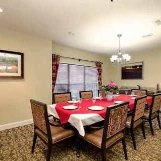 A beautifully decorated dining room with a long table set for a meal, featuring a red tablecloth and elegant chairs.