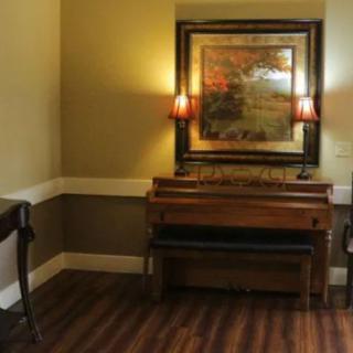 A cozy interior featuring a piano, wall art, and soft lighting from lamps.
