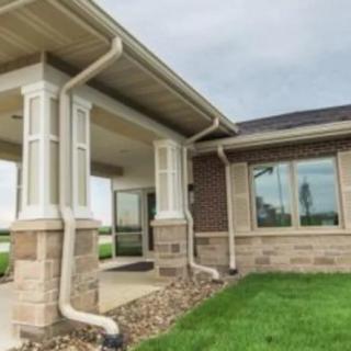 A view of a house exterior with a front porch and well-maintained lawn.