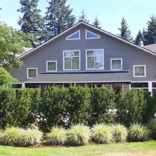 A suburban house surrounded by trees and shrubs on a sunny day.