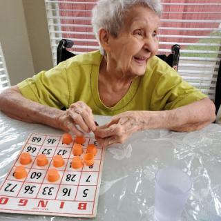 An elderly woman joyfully playing bingo.