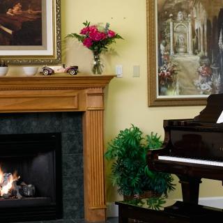 A cozy living room with a fireplace, grand piano, and vibrant artwork.