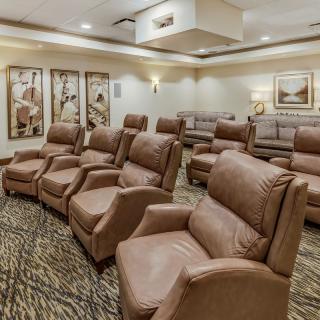 A luxurious home theater room featuring comfortable recliner chairs and ambient lighting, ideal for an immersive movie experience.