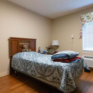 A cozy bedroom with a single bed, adorned with patterned bedding and surrounded by simple decor.