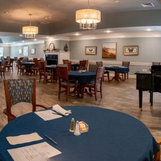 An elegant dining room with neatly arranged tables and chairs, adorned with chandeliers.