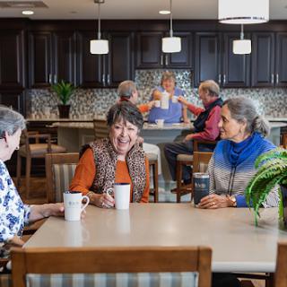 A vibrant senior living community where residents enjoy each other's company over coffee.
