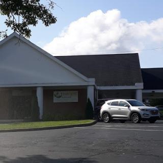 A modern building with a parked car in front on a sunny day.