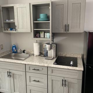 A modern kitchen setup with grey cabinets, a sink, and various appliances on the countertop.