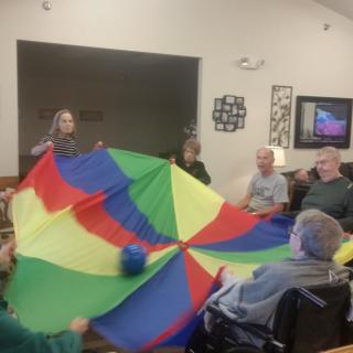 A group of elderly individuals engaging in a parachute game at a nursing home.