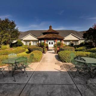 A scenic outdoor view of a building surrounded by well-maintained gardens and seating areas.