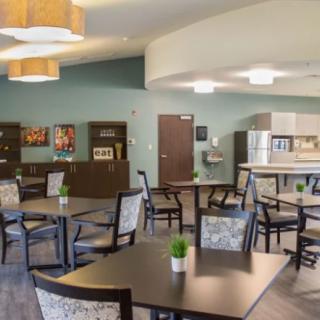 A modern dining and kitchen area with several tables and chairs.