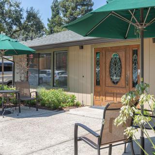 A cozy outdoor patio area with chairs, tables, and umbrellas in front of a building.