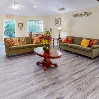 A cozy living room with two sofas, a central coffee table, and large windows providing natural light.