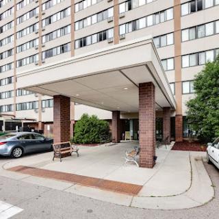 Entrance of a multi-story apartment building with a covered area for parking.