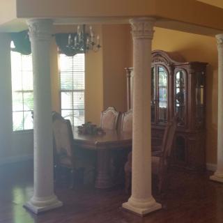 A dining room with elegant columns and a chandelier.