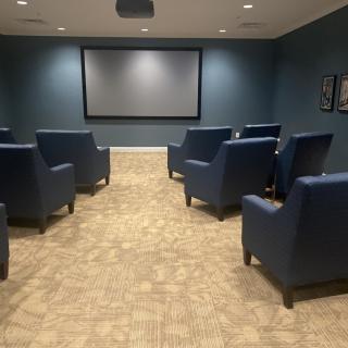 A small home theater with a projector screen and comfortable seating.