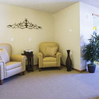A cozy living room with two armchairs and decorative elements, including a wall piece and an indoor plant.
