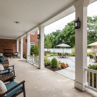 A spacious porch with outdoor seating overlooking a landscaped garden.