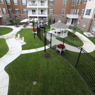 A view of a neatly landscaped apartment complex courtyard with pathways, a gazebo, and well-maintained grass.