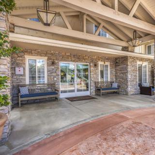 A welcoming building entrance with stone walls and benches on a covered porch.