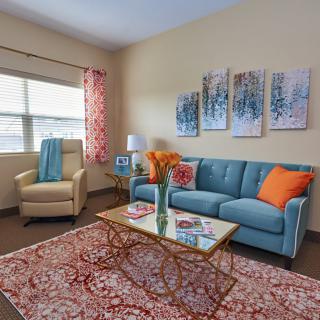 A cozy living room with a teal sofa, patterned rug, and colorful cushions.