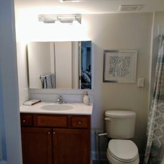 A well-lit bathroom featuring a sink, mirror, and toilet with modern decor.