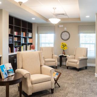A cozy lounge area with plush armchairs and a bookshelf, perfect for relaxing or reading.
