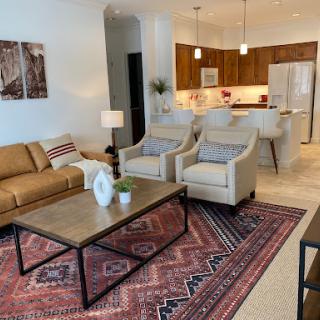 A stylish and modern living room featuring a cozy sofa and elegant chairs, complemented by a decorative coffee table and a patterned rug.