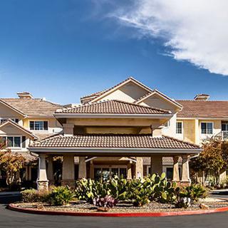 A residential building with a landscaped entrance under a clear sky.