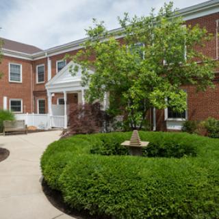 A peaceful courtyard featuring lush greenery and a brick building.