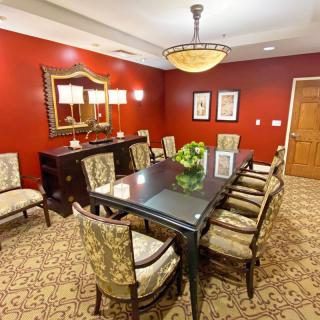 A well-decorated dining room with a dark wooden table, upholstered chairs, and warm red walls.