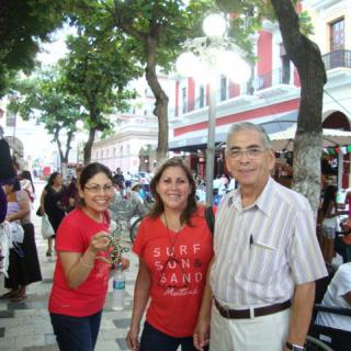 A group of people smiling while walking on a tree-lined street.
