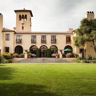 A picturesque mansion surrounded by lush green lawns and elegantly designed gardens.