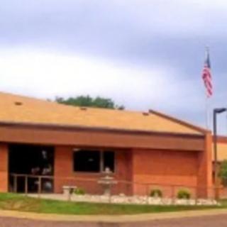 A brick building with an American flag flying outside on a cloudy day.