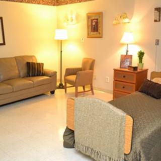 A cozy bedroom with a bed, sofa, and lamps providing warm lighting.