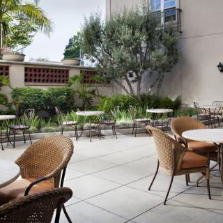 An outdoor patio area with tables and chairs surrounded by greenery.