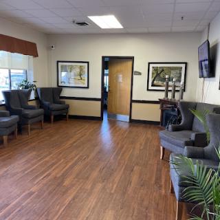 A cozy waiting room featuring comfortable seating, wooden floors, and artwork on the walls.