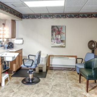 A small hair salon interior with chairs, a sink, mirror, and wall art.