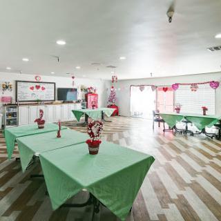 A spacious event space decorated with green tables and festive decorations, ready for a celebration.
