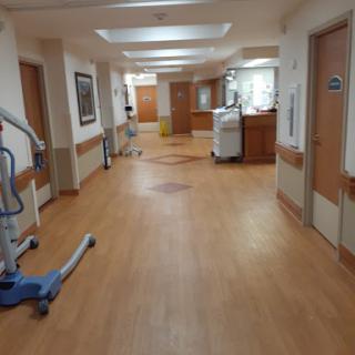 A spacious corridor inside a hospital, featuring wooden flooring and various healthcare equipment.
