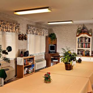 A cozy interior space featuring a table, bookshelves, and plants.