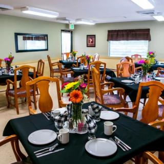 A well-arranged dining room with tables set for a meal, featuring flowers as centerpieces.