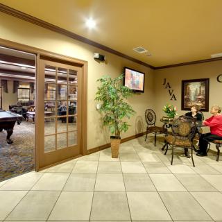 A cozy lobby area with seating, a television, and decorative plants.