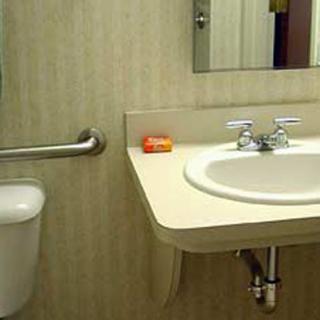 A bathroom with a sink, mirror, and soap on the counter.