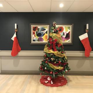 A beautifully decorated Christmas tree surrounded by festive stockings and colorful artwork.