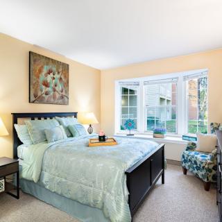 A cozy bedroom with a large window, featuring a neatly made bed and stylish decor.