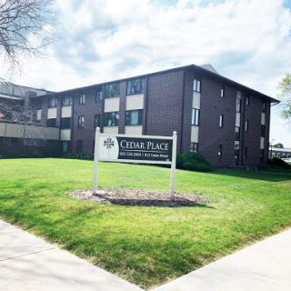 A view of an apartment complex featuring a welcoming sign and well-maintained lawn.