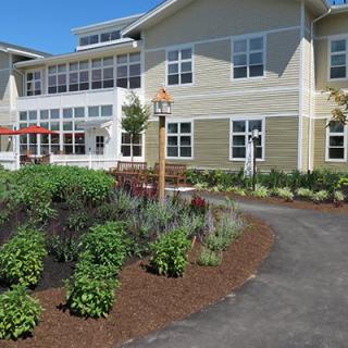 A well-landscaped garden with a pathway leading to a residential building on a sunny day.