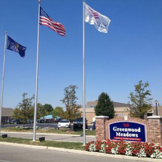 Outdoor view of Greenwood Meadows with flags and signage.